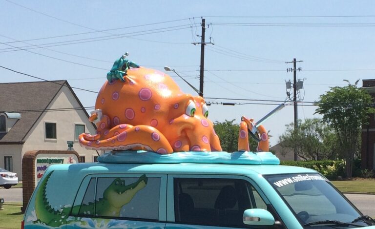 Giant orange 3D octopus bursting through a car roof.