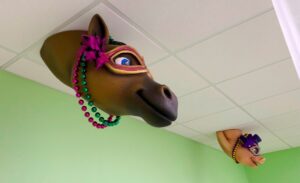 ceiling tiles in medical treatment bay featuring carnival themed race horse and pig head sculptures