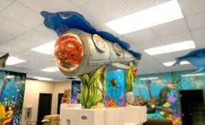 Custom foam carved submarine mounted to the ceiling of a dental treatment bay with octopus character inside.