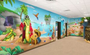 Full wall mural in kids area of custom pirate theme featuring a beach theme with buried treasure and crocodiles