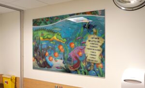 Large I spy graphic with a river theme hanging on the wall in a hospital waiting room