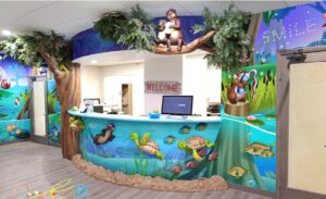 Medical reception desk clad with sculpted animals and underwater river murals