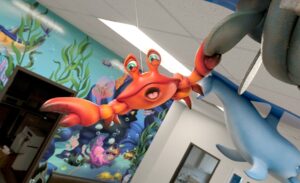 Surprised red crab hanging from a submarine propeller above a pediatric treatment bay