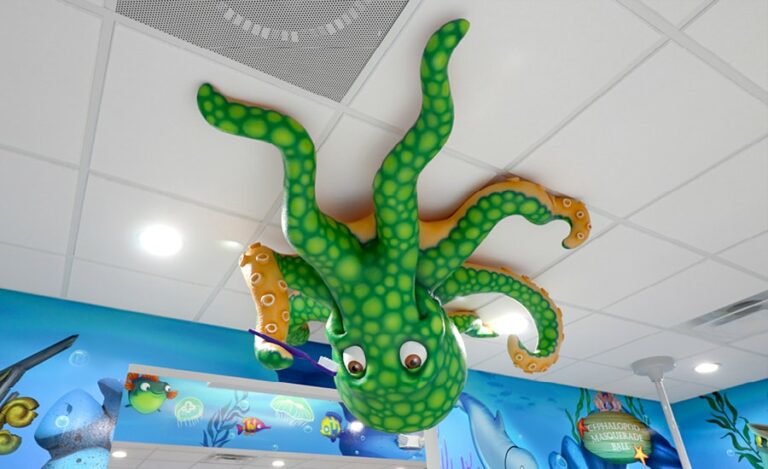 A bright green spotted sculpted octopus holding a toothbrush mounted upside down on ceiling in a dental office