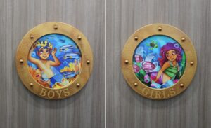 Bathroom signs made like ship portholes with colorful murals in a pediatric clinic