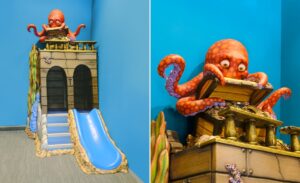 close up of cute octopus character opening treasure chest above a slide in kids play area