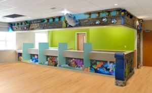 dental reception desk with underwater-themed murals and desk cladding in family-friendly medical clinic