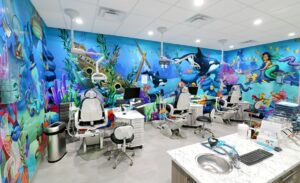 Dental treatment bay surrounded by a vivid mural of playful underwater life including fish, whales and mermaids