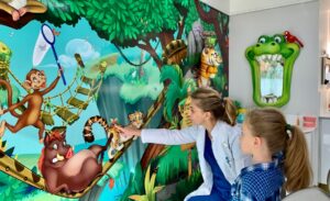 Dentist and patient looking at jungle murals in kid-friendly dental practice