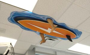 funny surfer and surfboard sculpture hung from the ceiling of kids dental office