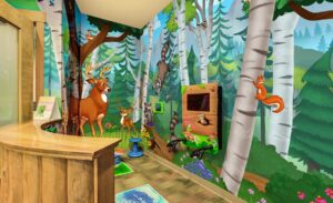 kid friendly woodland murals and gaming units in pediatric waiting room