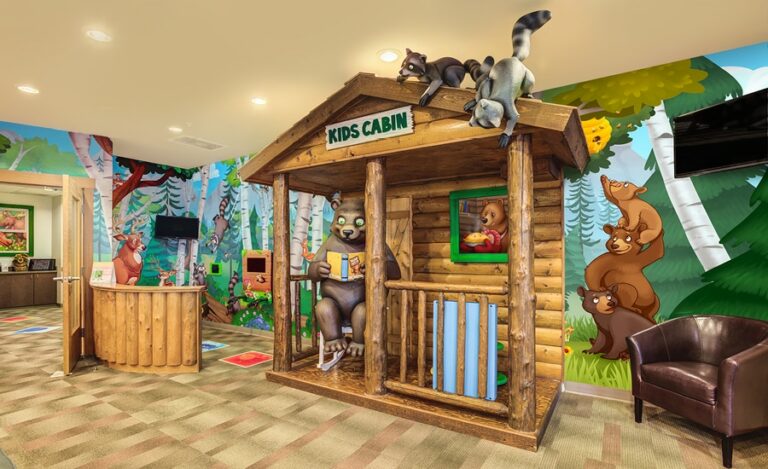pediatric waiting room with cabin play area, cute sculpted bear characters, and woodland murals