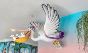 sculpted pelican mother character carrying babies above pediatric office reception
