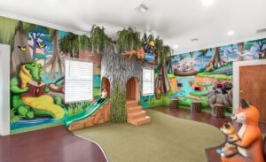 themed kids play area in an office with prop bayou trees and wall murals
