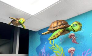 Turtle and baby turtle sculptures and ocean themed murals in kids dentist office
