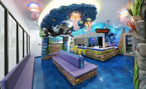 Undersea themed dental office waiting room with ceiling mounted jellyfish lights, colorful fish, and sculpted coral benches