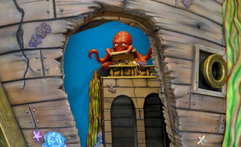 view through an archway of red octopus opening a treasure chest in a play area
