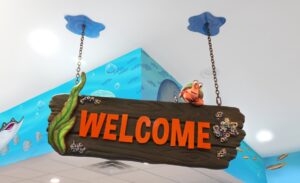 Welcome signage with bright lettering and a cute hermit crab suspended above the reception desk for a kids dentistry
