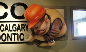 sculpted construction worker putting together a company sign for orthodontic practice