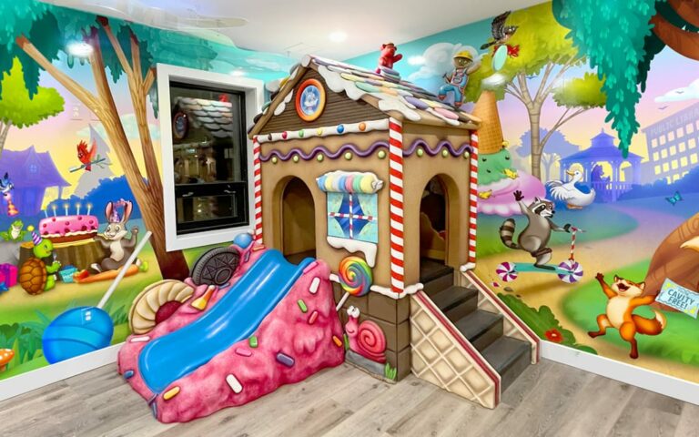 A gingerbread themed play house with big blue slide for small children. A gingerbread themed play house with slide for small children. Candy accessories decorate the office.