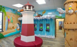beach themed pediatric waiting room with murals wave sculpture and lighthouse themed bench