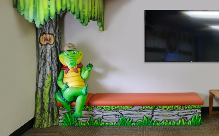 Alligator photo op character sitting on a bench in a pediatric medical clinic.