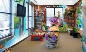 pediatric waiting room with jungle murals, hippo character, and sculpture of girl rock climbing