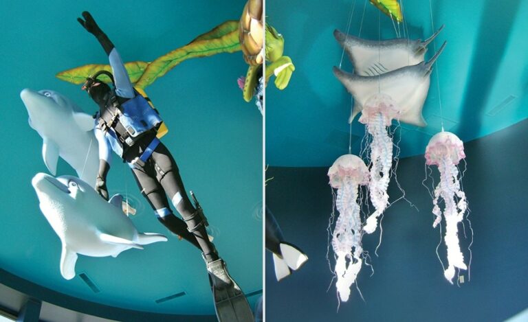 closeup of a sculpted scuba diver with dolphins stingray and jellyfish swimming around him