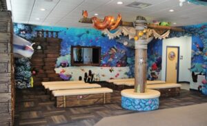 dental office theater room area with sunken ship wall covering and wooden benches