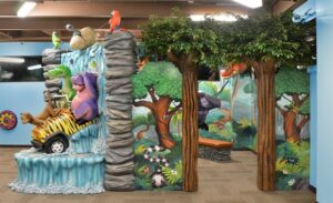 entrance to a pediatric office games room with jungle murals and trees with faux leaves