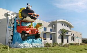 exterior landmark sculpture of orca and crocodile driving jeep through office wall
