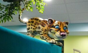 friendly jungle cat on top of a themed boat in central area overlooking a dental open bay