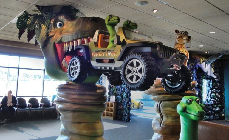 giant sculpted trex head and dinosaur driving a jeep in kids dental theater