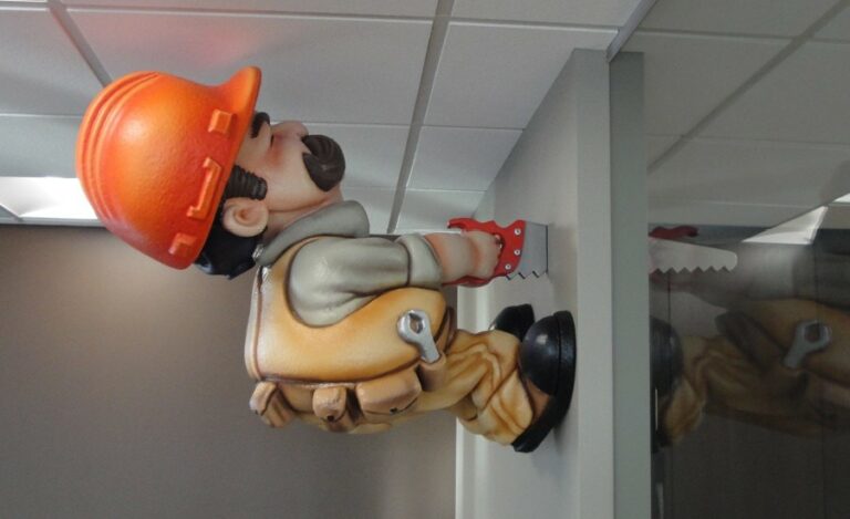 sculpted hardhat construction worker character sawing through the wall in a kid friendly office