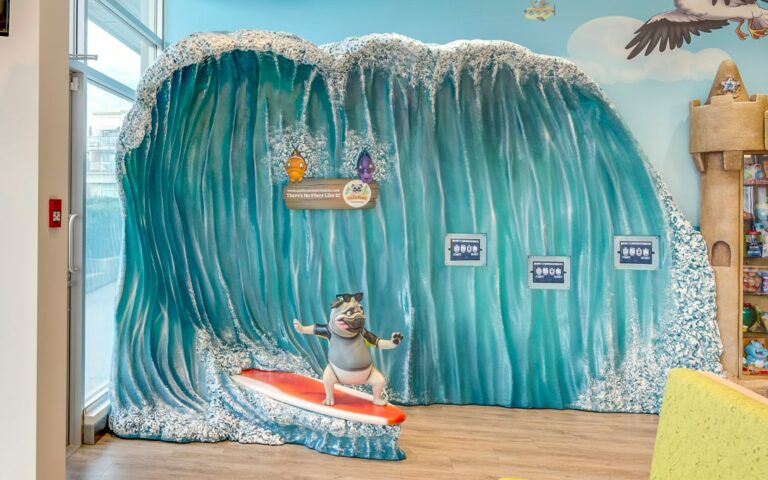 A pug in a wetsuit surfing a wave used as a photo op for children visiting a dental office