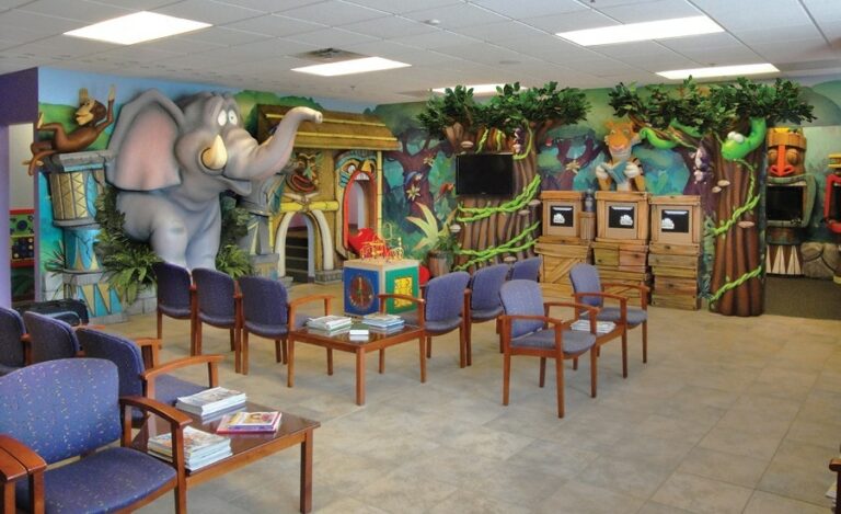 jungle themed waiting room for kids with sculpted elephant busting through the wall and custom gaming units