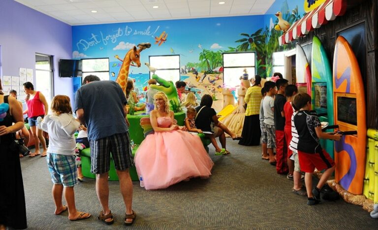 kids in beach themed pediatric waiting room with surfboard shaped gaming units and custom murals