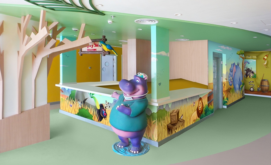 Savannah-themed wall murals, sculpted hippo character wearing medical scrubs and contemporary trees for children's hospital unit desk.