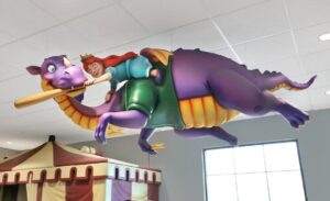 purple dragon sculpture with princess riding his back suspended from the ceiling in kids dental office