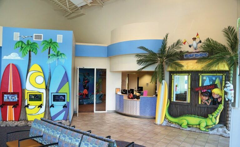 reception area with surf shack theme next to kids gaming area with surfboard shaped wall mounted gaming units