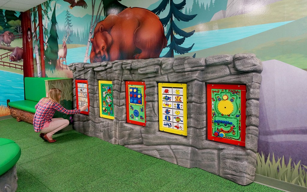 Woodland rock game wall with Keebee play boards and video games.