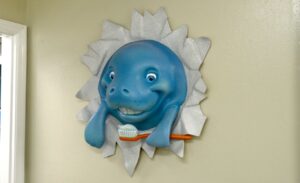 sculpture of toothbrushing manatee busting out of wall in a dental clinic