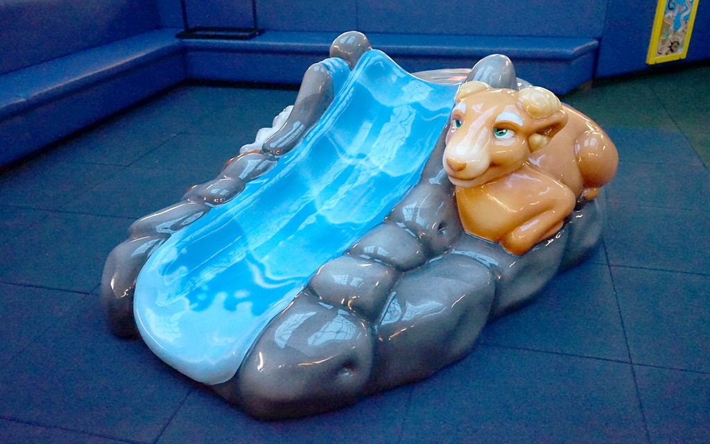 Soft play foam sculpture slide with a goat sitting on a mountain side.