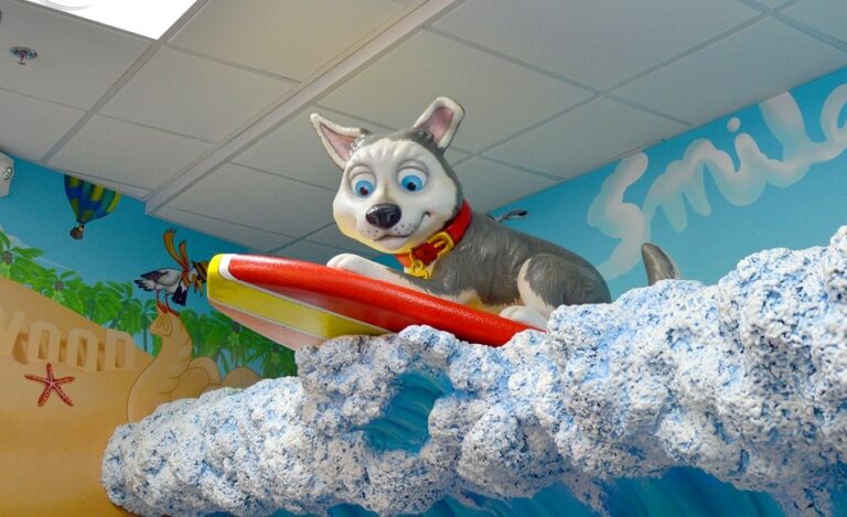 surfing sculpted puppy mascot riding a sculpted wave in a kid friendly dental clinic