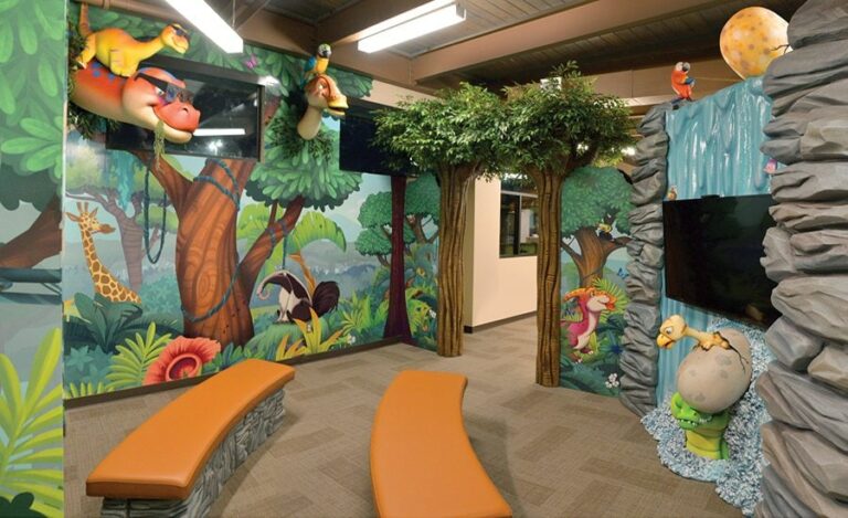 theatre room for a kid friendly dental clinic with sculpted rock cladding and fun dinosaur filled wall murals