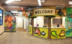 themed reception desk surrounded by sculpted dinosaurs and jungle animals with friendly murals