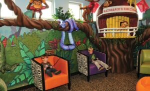 tropical forest games room with large sculpted treehouse filled with friendly animal characters