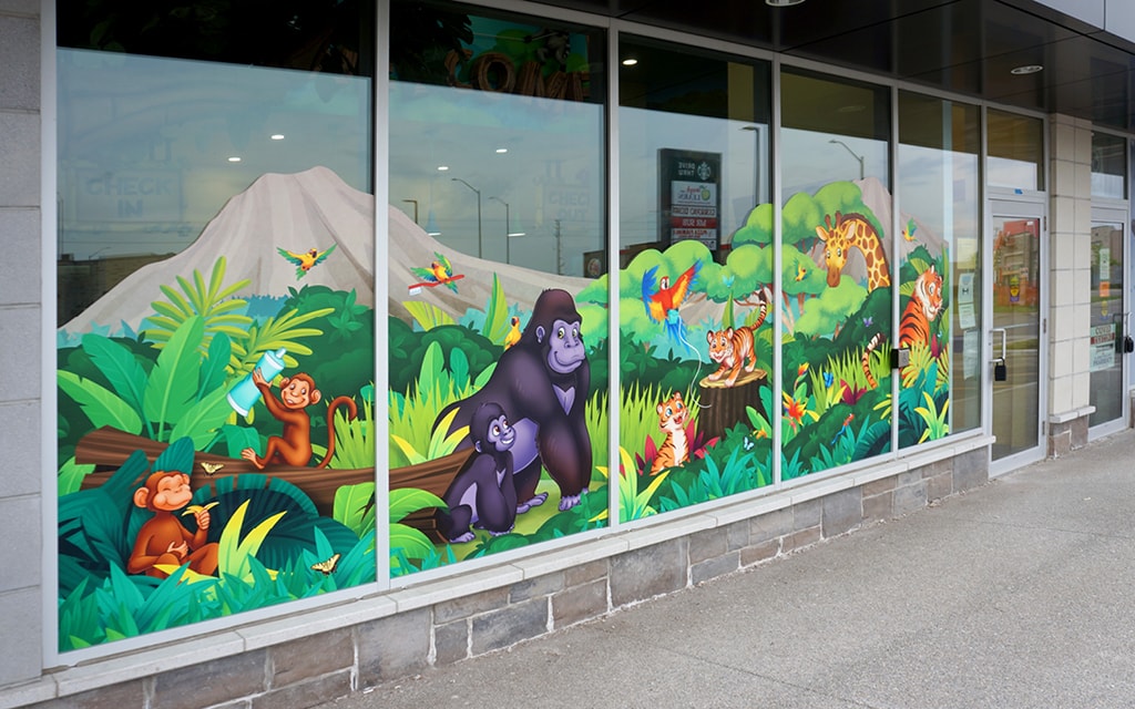 An exterior window decal featuring a cartoon jungle scene with gorillas, monkeys, and tigers.