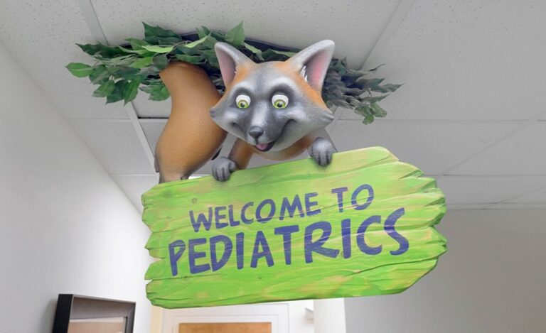 custom wayfinding signage roof tile with a cute raccoon character holding a “welcome to pediatrics” sign