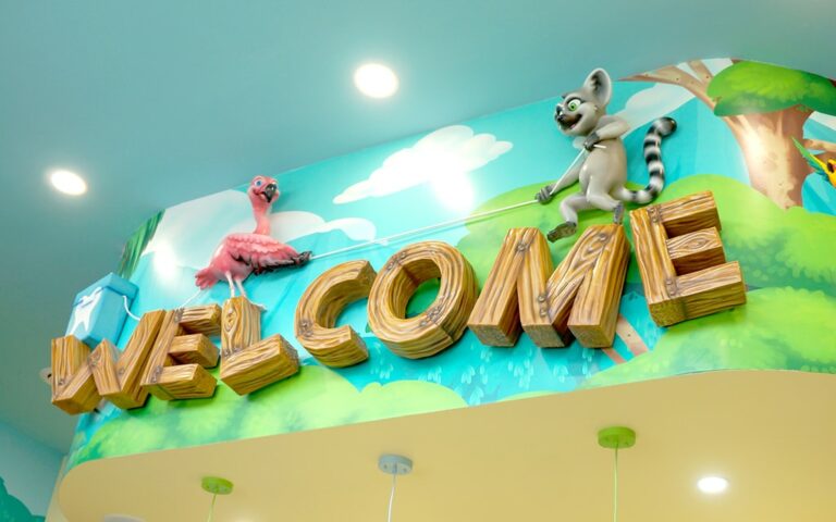Custom "Welcome" sign with a flamingo and lemur playing tug of war with floss.